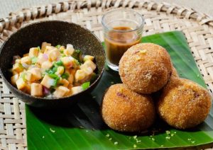 Bolinho bahia: três bolinhos bahia ao lado de uma cumbuca com vinagrete e um copinho com molho de pimenta