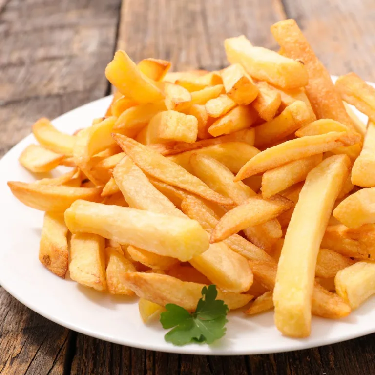 como deixar a batata frita sequinha: prato branco com batatas fritas crocantes.