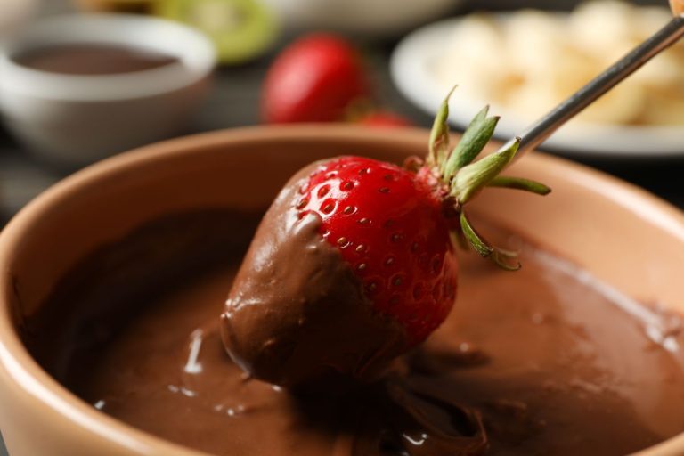 espetinho de morango com chocolate: morango em uma palito sendo banhado no chocolate.