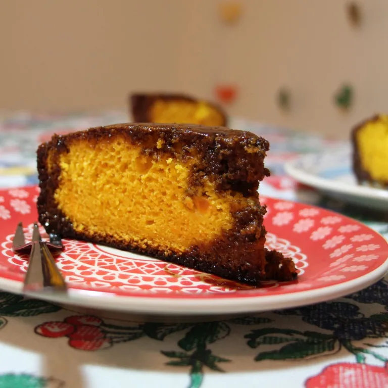 receita de bolo de cenoura de liquidificador: Fatia de bolo em um prato e um garfo ao lado.