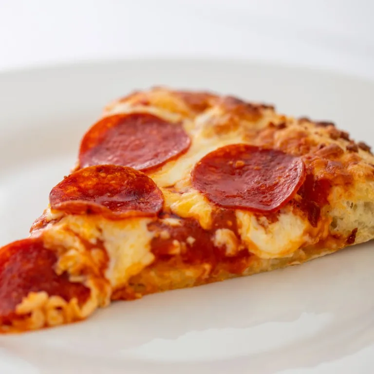 receita de pizza de liquidificador: uma fatia de pizza caseira de calabresa em um prato branco.