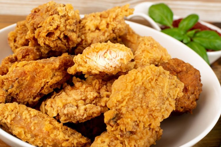 receita de frango empanado crocante: vários pedaços de frango empanados em um prato branco.