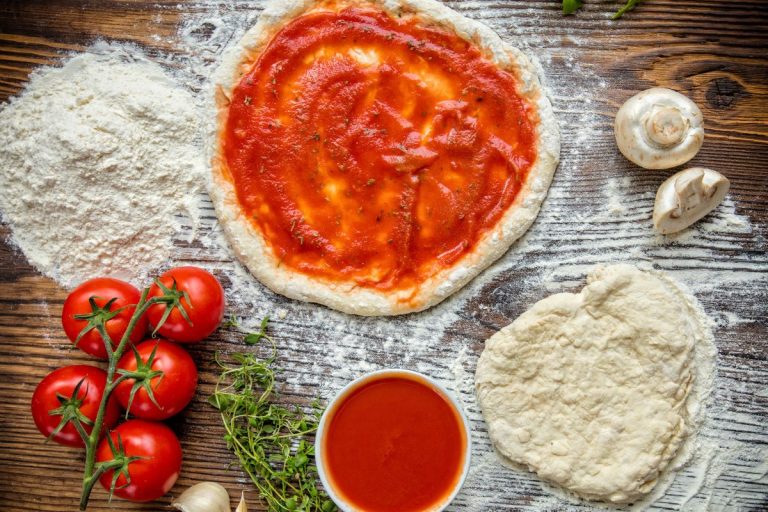 receita de massa de pizza: massas de pizzas sendo abertas em uma superfície polvilhada com farinha. Tomates ao lado