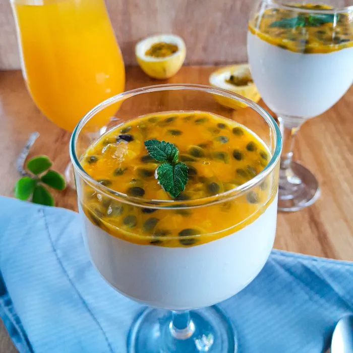 como fazer mousse de maracujá: duas taças com mousses decoradas com uma folha de hortelã e uma taça ao fundo com suco de maracujá