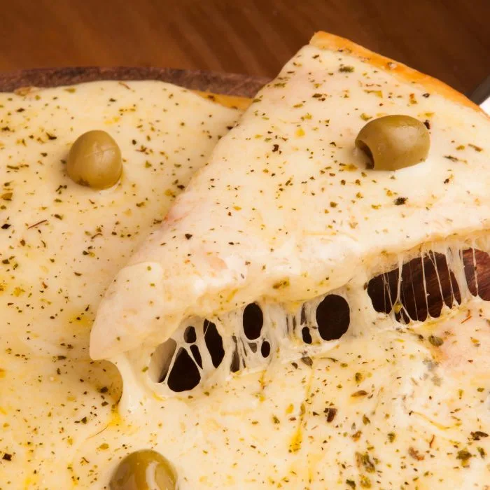 receita de pizza caseira: pizza de mussarela sendo cortada uma fatia