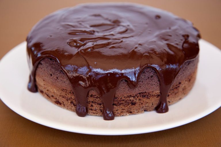 receita pequena de bolo de chocolate: bolo de chocolate com calda em um prato branco.
