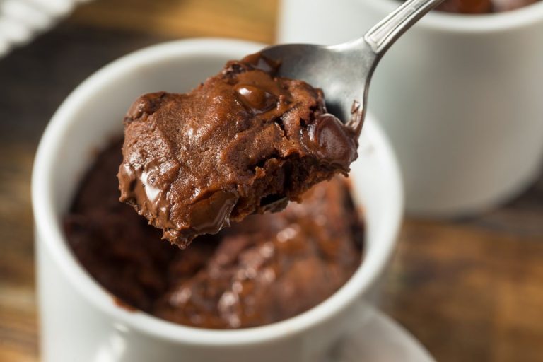 como fazer brownie de caneca: delicioso brownie quentinho em uma caneca branca pronto para ser consumido.