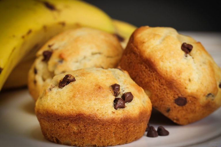 bolinho fit de banana com gostas de chocolate em um prato com uma banana ao lado.