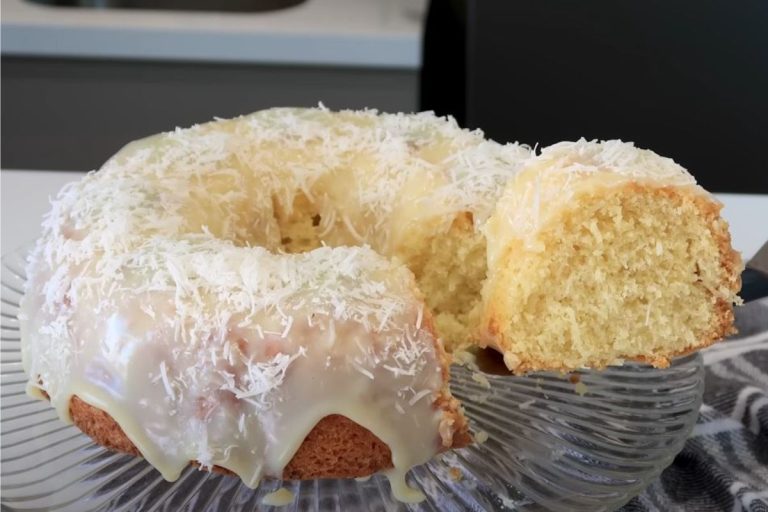 bolo de coco com cobertura sendo fatiado para ser servido.