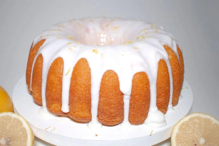 bolo de laranja com cobertura branca de açúcar e laranjas ao redor.