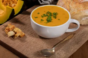 caldo de abóbora cabotiá em uma tigela com uma colher ao lado.