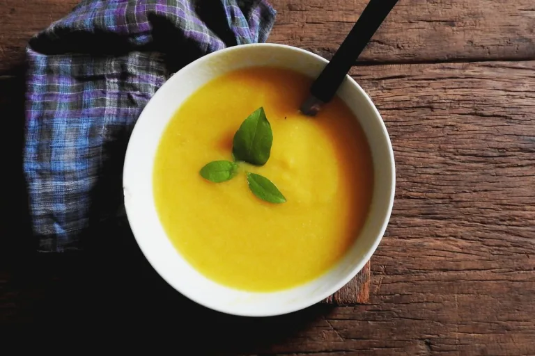 caldo de mandioquinha em uma tigela branca com uma colher pronto para ser servido.