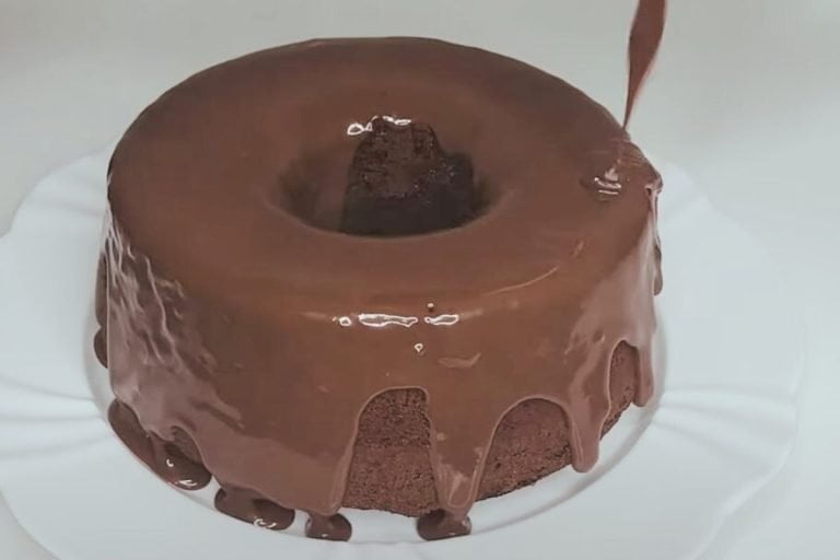 cobertura de chocolate sendo despejada sobre o bolo.