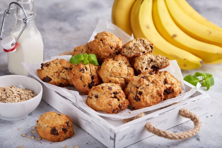 receita cookies saudável: cesta com cookies deliciosos. Um Cacho de bananas ao lado, uma garrafa de leite e aveia.