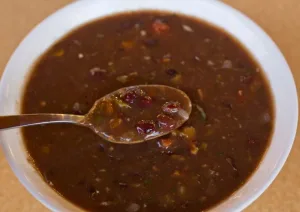 prato com caldo de feijão preto e uma colher.