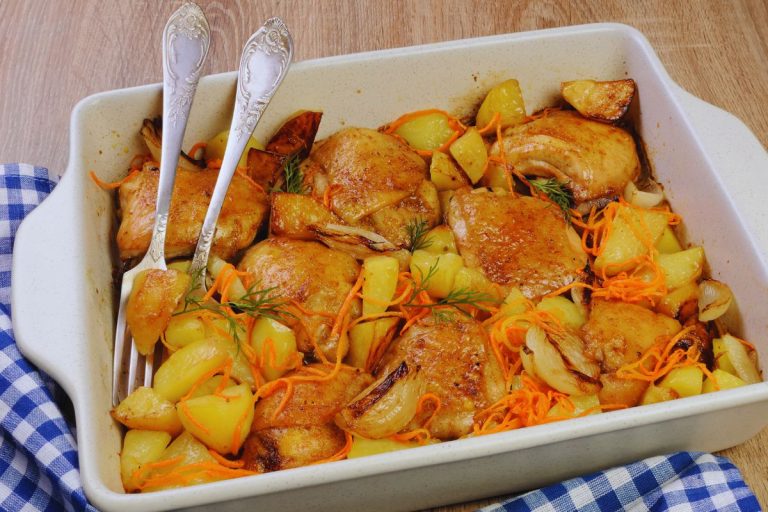 Delicioso frango assado em uma travessa com batatas, cebolas e cenoura.