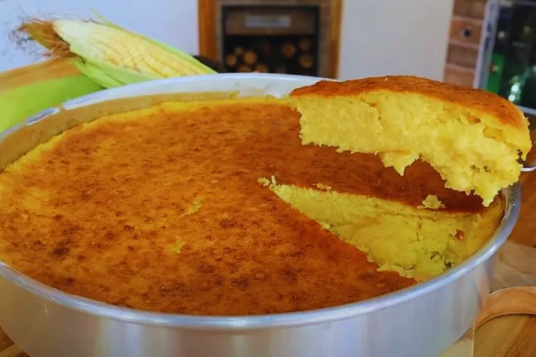 Receita de bolo de milho verde: assadeira redonda com bolo de milho verder sendo retirada uma fatia para servir.