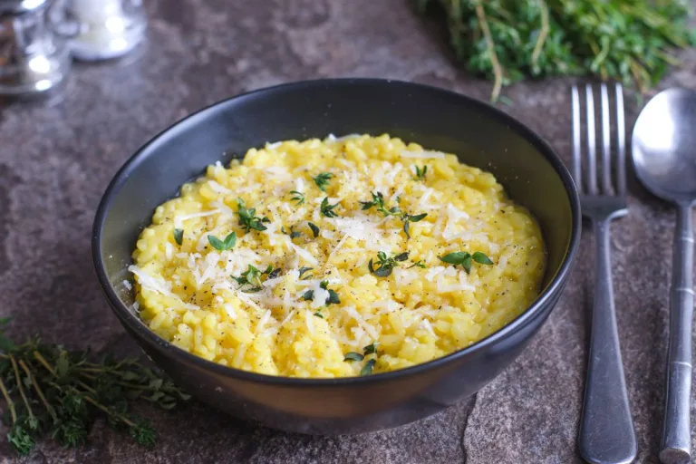 receita de risoto de palmito em uma tigela preta sofisticada com talheres ao lado.