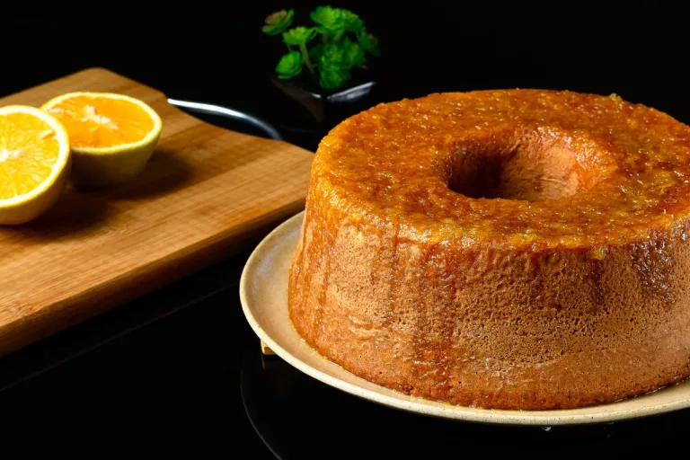 receita de bolo de laranja: delicioso bolo de laranja com calda em um prato com laranjas ao redor.