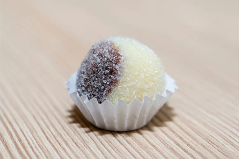 receita de brigadeiro casadinho: um brigadeiro casadinho em uma forminha branca sobre a mesa.