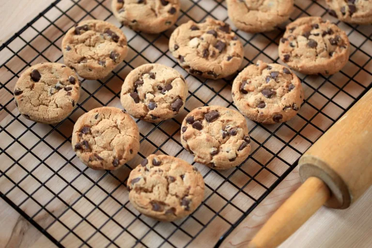 receita de cookies: vários cookies com gotas de chocolate em uma grade esfriando e um rolo de macarrão ao lado.