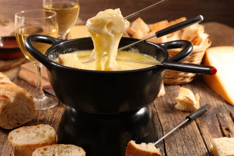 receita de fondue de queijo: réchaud com creme de queijo sendo degustado com pedaços de pão