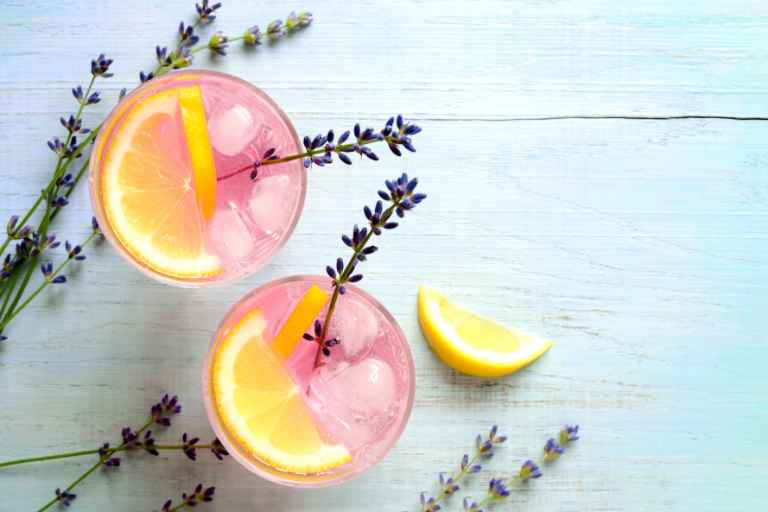 Origem/História da Receita: dois copos com limonada de lavanda e ramos de lavanda decorando.