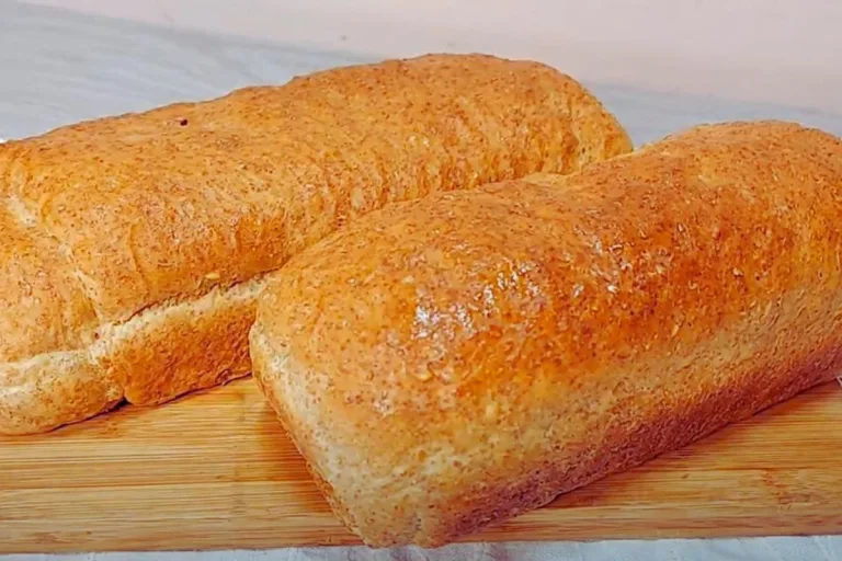 receita de pao integral: Dois pães integrais em cima de uma tábua de madeira.