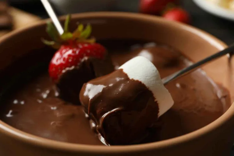 receita de fondue de chocolate: morango e marshmallow sendo mergulhados no chocolate derretido.