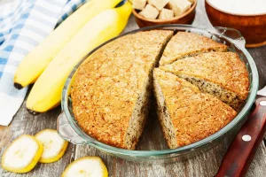 receita de torta de bananas: torta de banana fatiada em uma forma com bananas ao lado